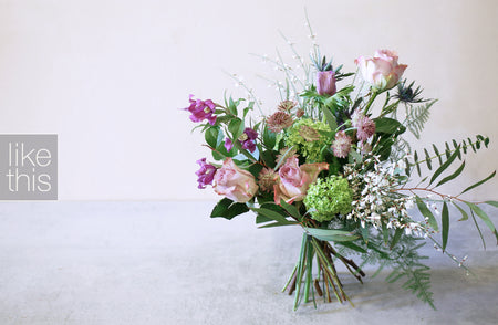 A bouquet of lilac and lime flowers arranged naturally, including roses and other greenery, presented in a like-this text box.